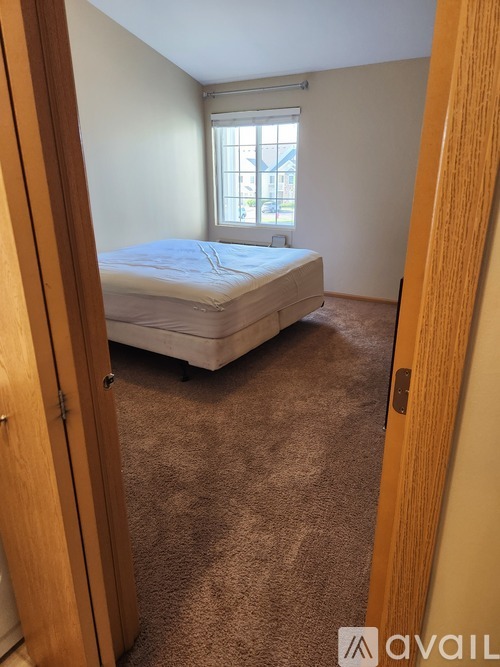 A bedroom with a bed, carpet, and a window.