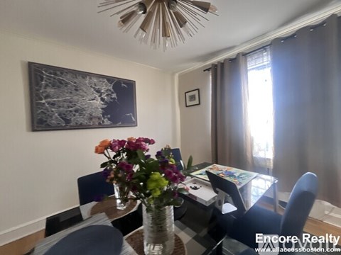 A dining room with a table set for four and a painting on the wall.