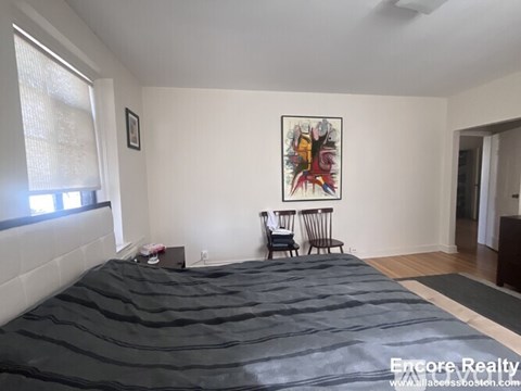 A bedroom with a large bed and a painting on the wall.