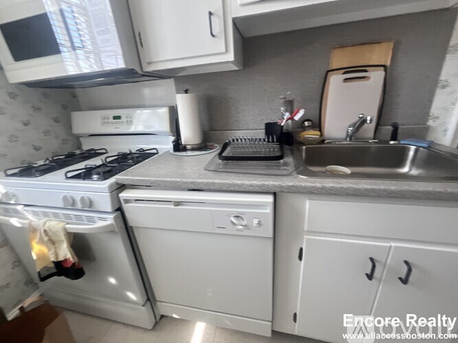 A white stove and oven in a kitchen with a sink and microwave.