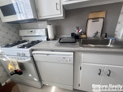 A white stove and oven in a kitchen with a sink and microwave.