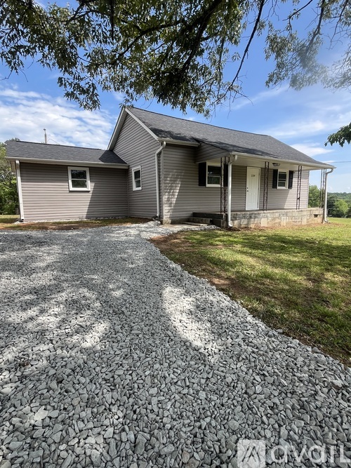 A house with a grey roof and a gravel driveway in front.