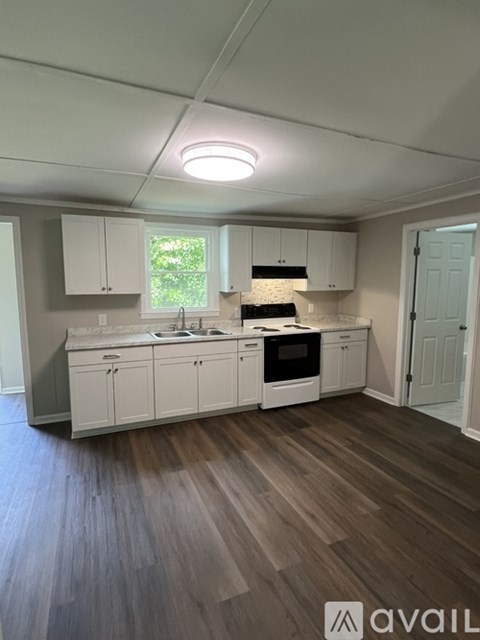 A kitchen with white cabinets and a wooden floor.