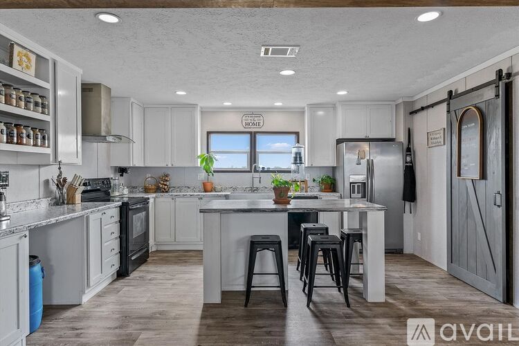 A kitchen with a large island and a refrigerator with a door that is open.