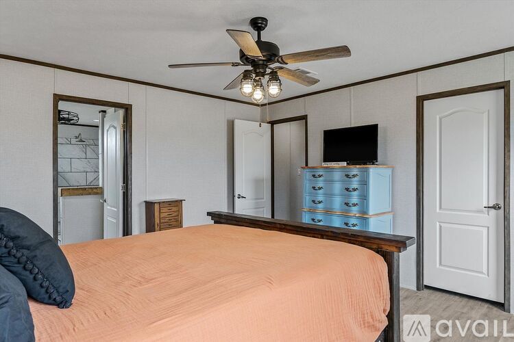 A bedroom with a bed, dresser, and a ceiling fan.