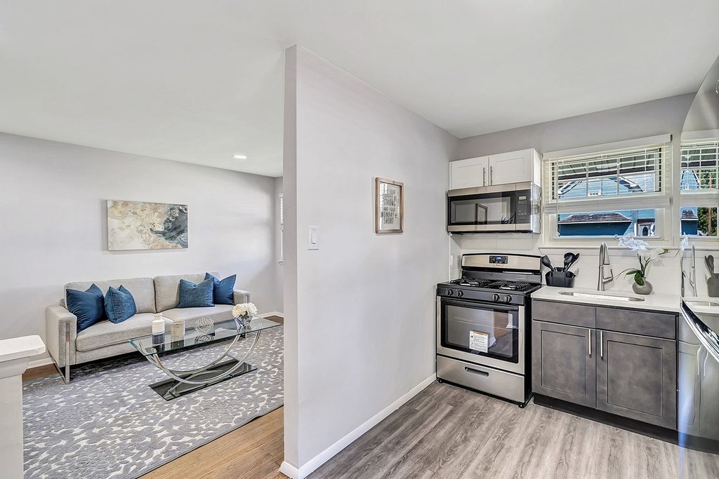 A modern kitchen with a grey sofa and a painting on the wall.