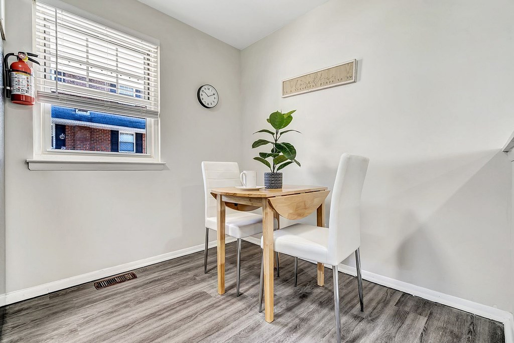 A small dining room with a wooden table and white chairs.