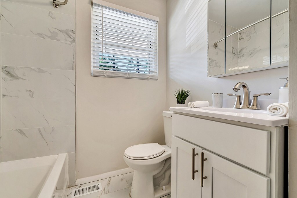 A white bathroom with a toilet, sink, and tub.
