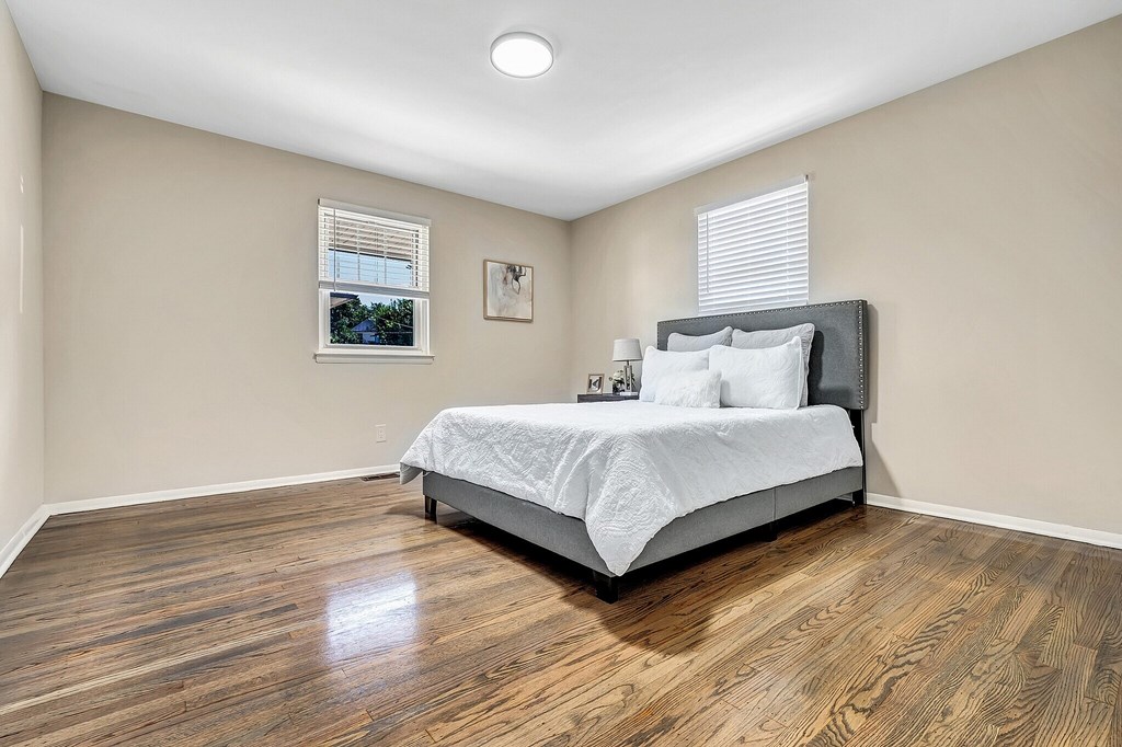 A bedroom with a bed, pillows, and a picture on the wall.