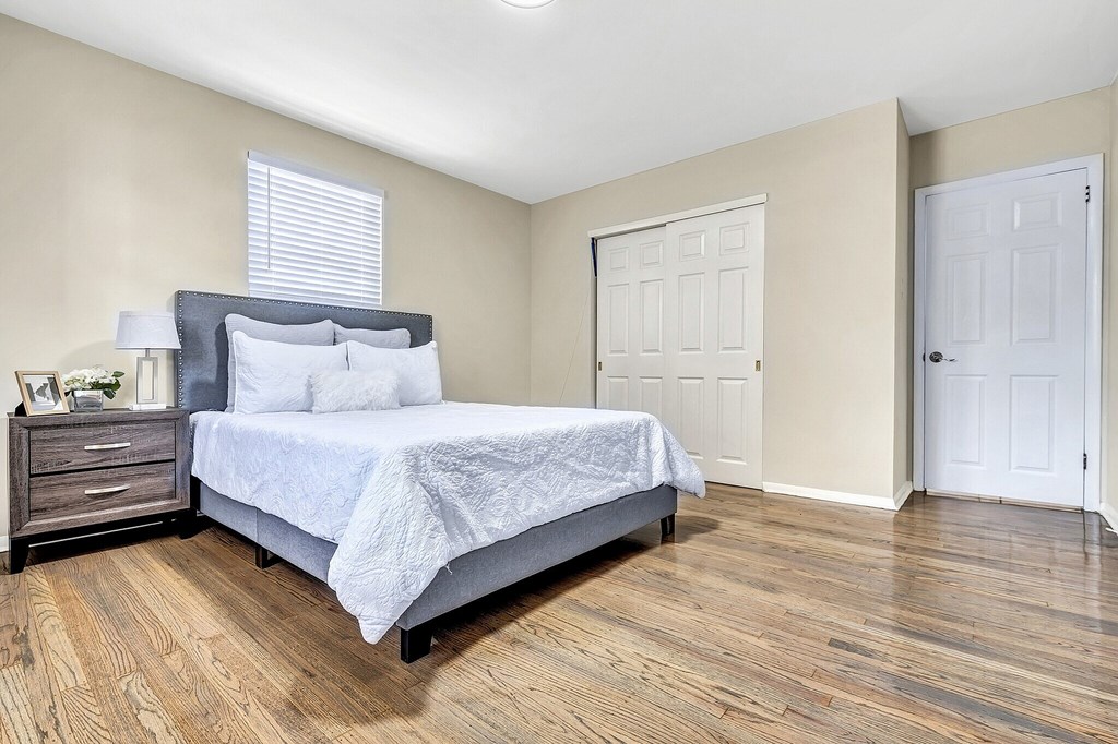 A bedroom with a bed, nightstand, and two doors.