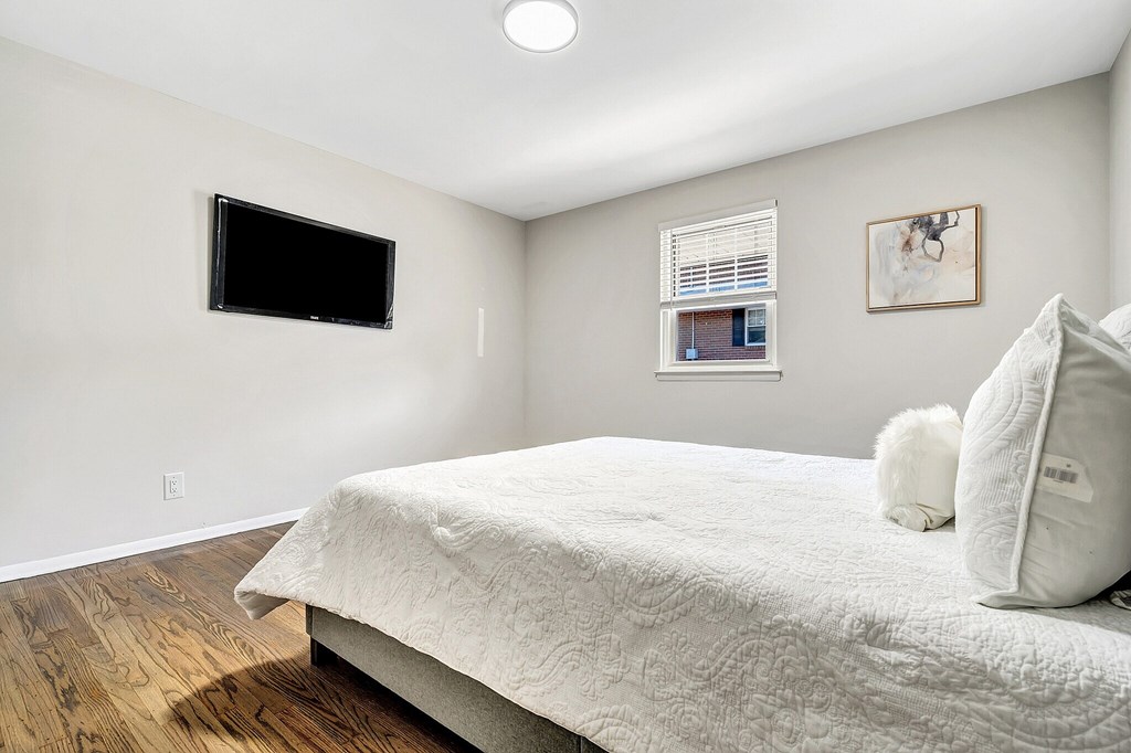 A white bed with a white pillow and a white cat on it.