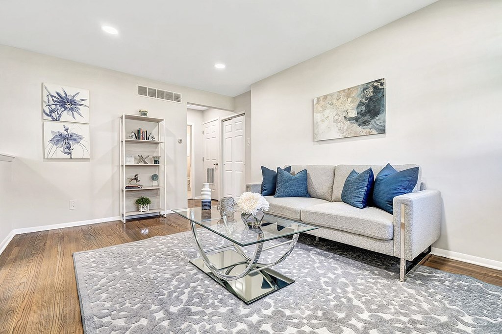 A living room with a white couch and a glass coffee table.