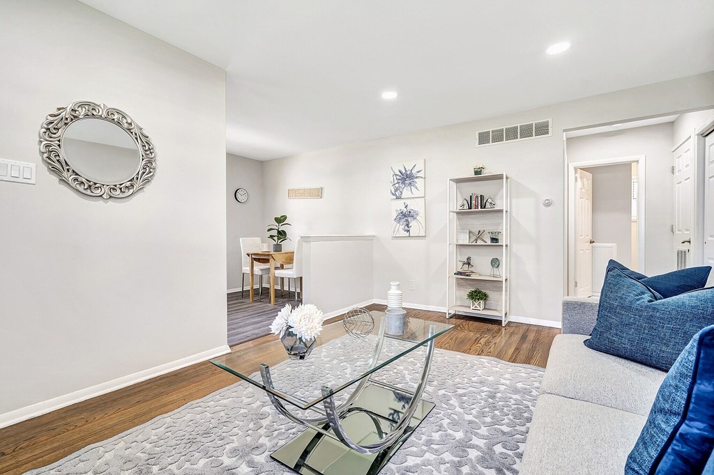 A living room with a glass coffee table and a blue cushion.