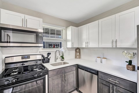 A modern kitchen with a stainless steel oven and white cabinets.