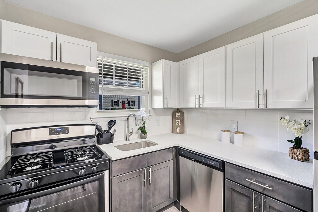 A modern kitchen with a stainless steel oven and white cabinets.