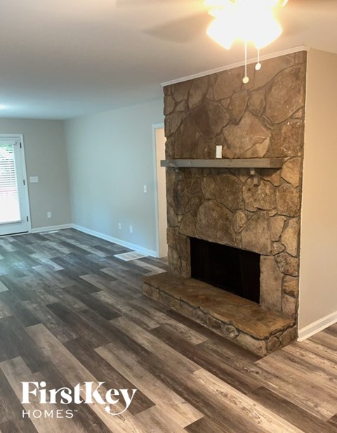 A stone fireplace in a room with wooden flooring.
