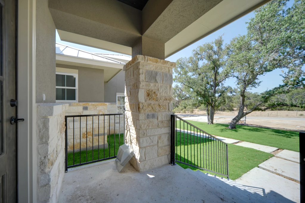 A stone pillar stands in the middle of a concrete patio.