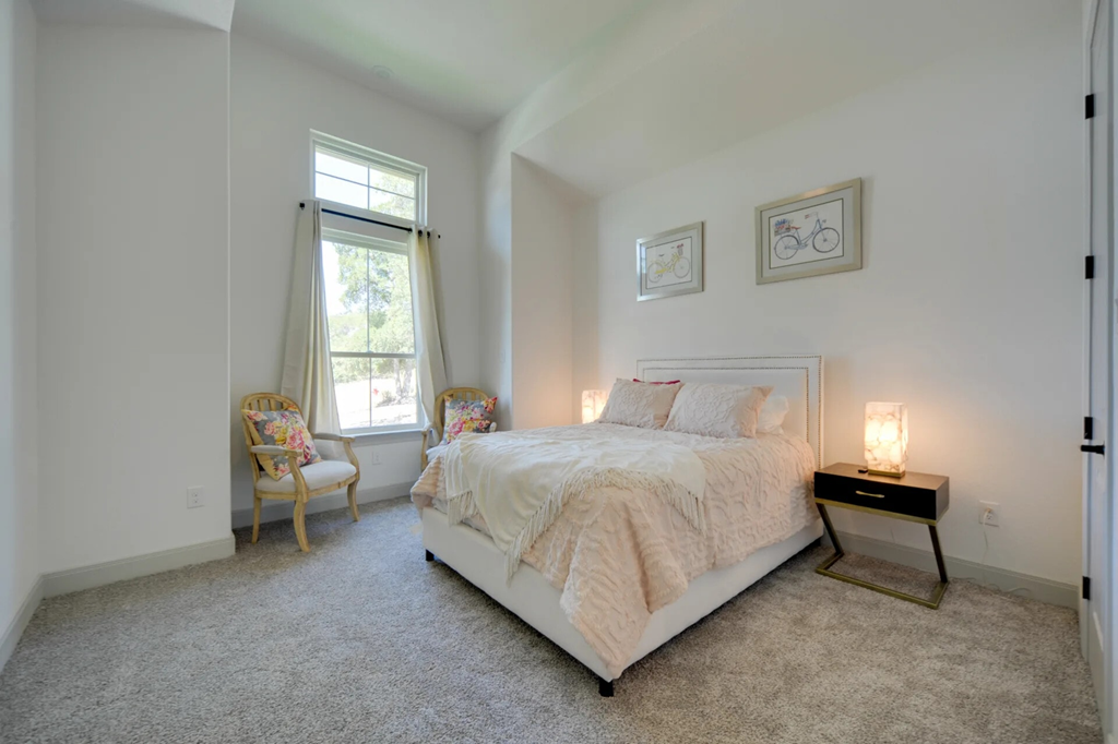 A bedroom with a large bed and a chair by the window.