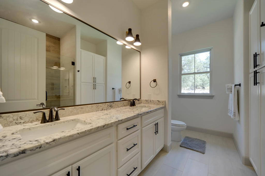 A bathroom with a marble countertop and white cabinets.
