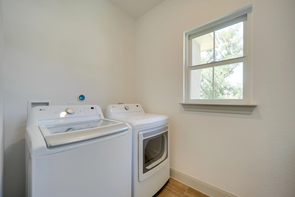 A white washing machine and dryer in a small room with a window.