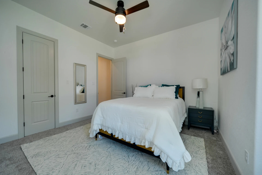 A bedroom with a bed, nightstand, and a ceiling fan.