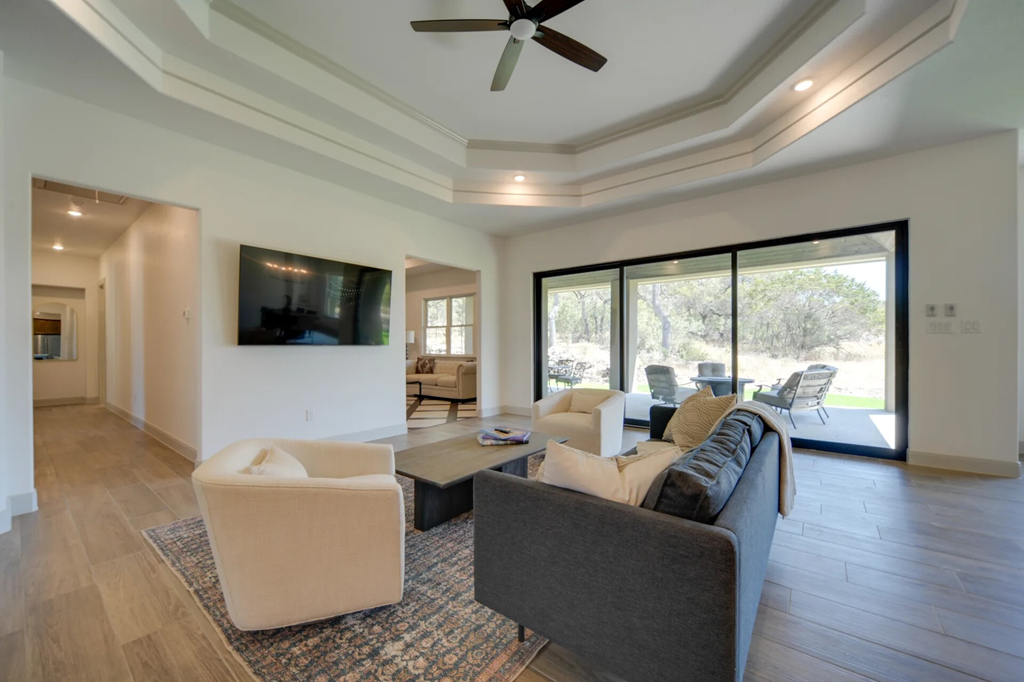 A living room with a grey couch, a white chair, and a television mounted on the wall.