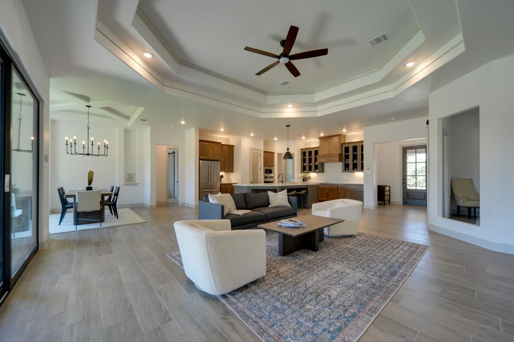 A spacious living room with a large rug and a ceiling fan.