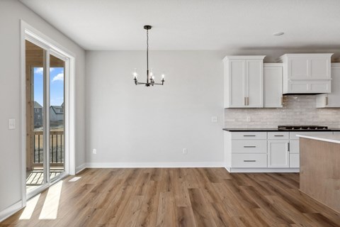 A kitchen with white cabinets and a wooden floor.