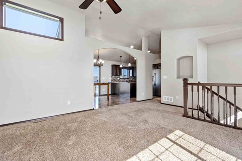 A spacious living room with a ceiling fan and a large window.