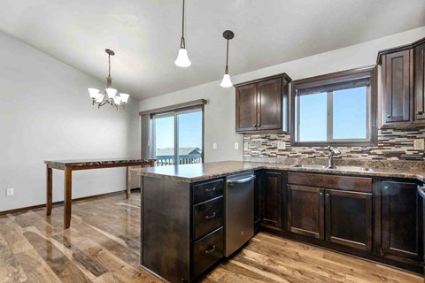 A kitchen with dark wood cabinets and a granite countertop.