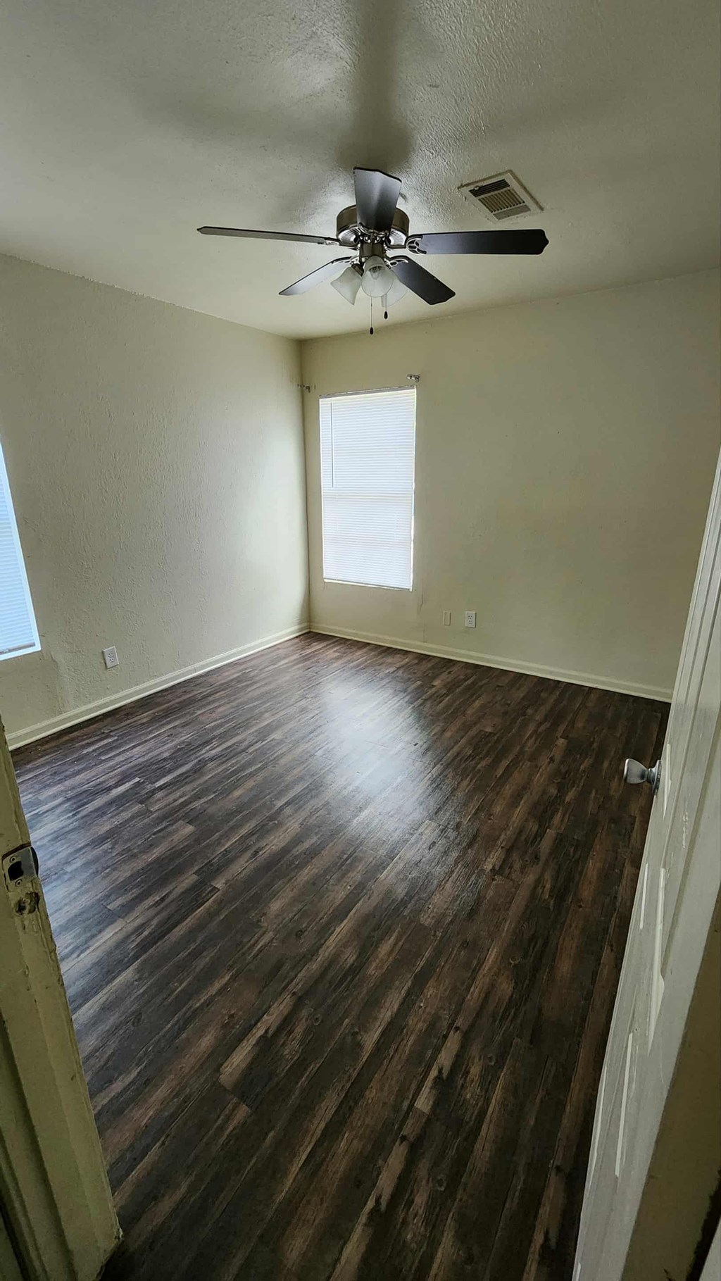 A room with a ceiling fan and wooden flooring.