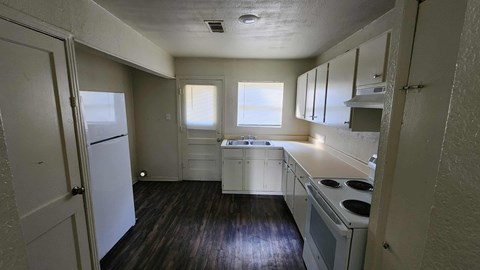 A kitchen with white appliances and wooden floors.
