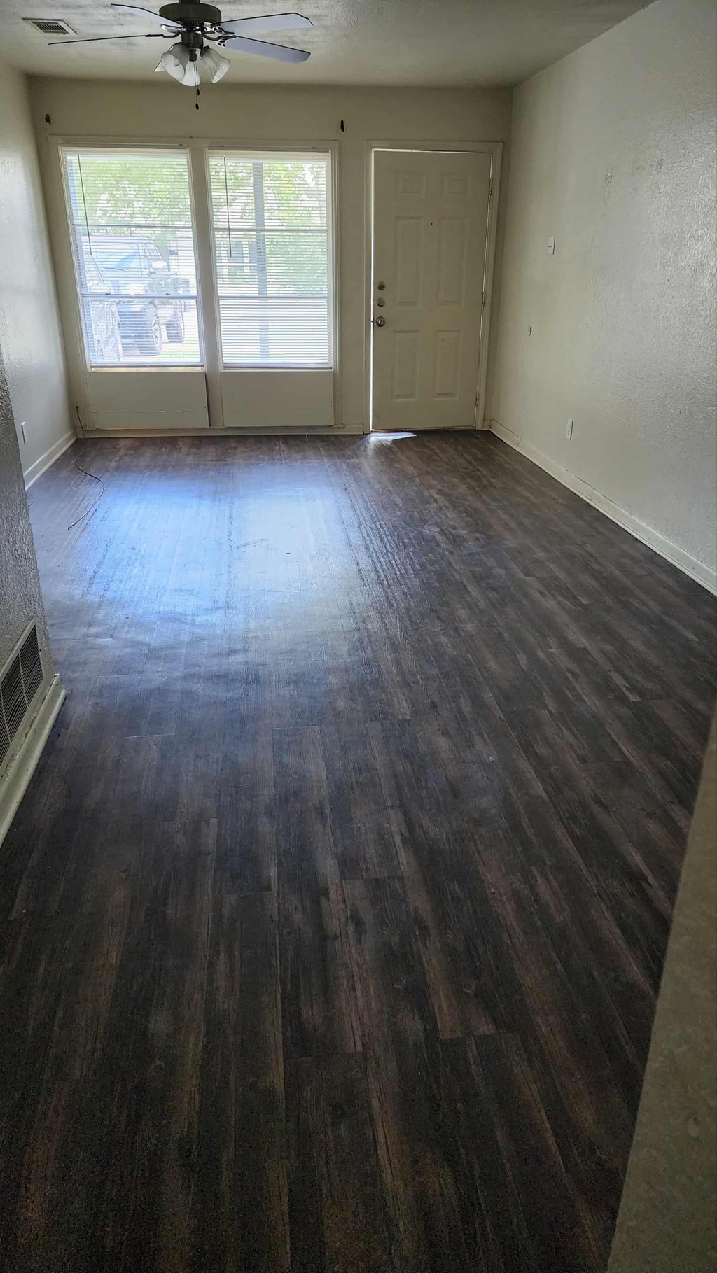 A room with a ceiling fan and sliding glass doors.