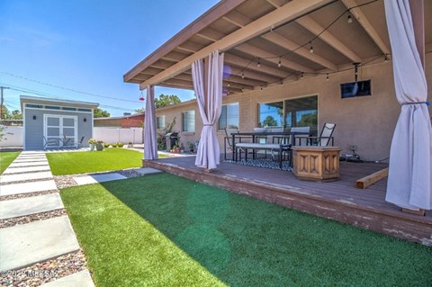 A patio with a white canopy and a table with chairs under it.