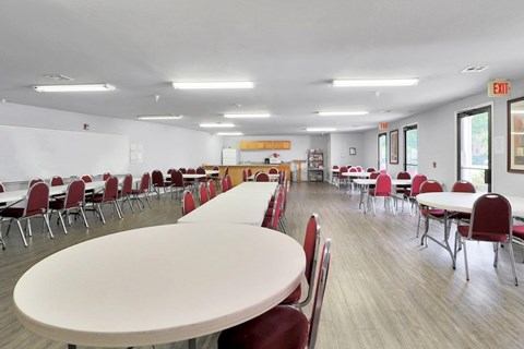 A white table with red chairs in a room with a white wall and a yellow sign.