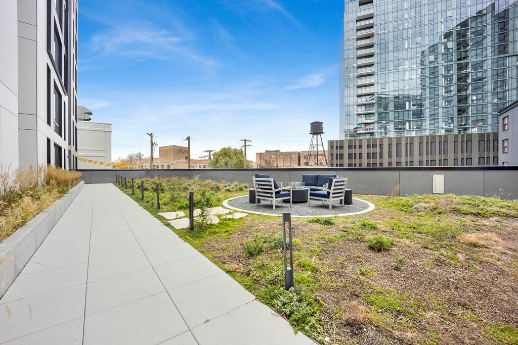 A rooftop patio with a table and chairs overlooks a cityscape.