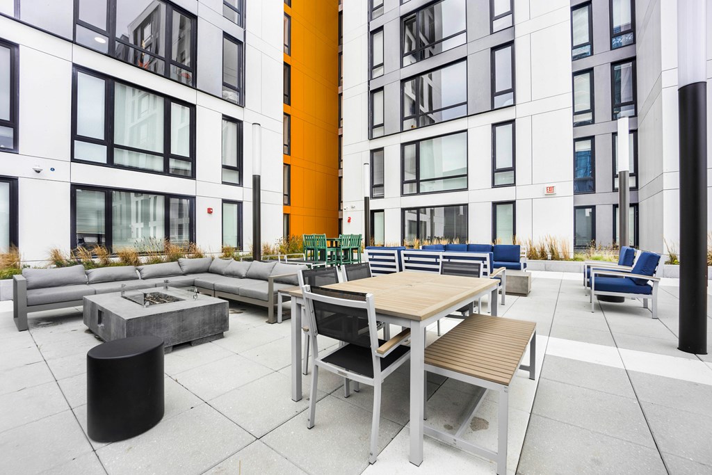 A modern outdoor seating area with a variety of furniture including tables and chairs.