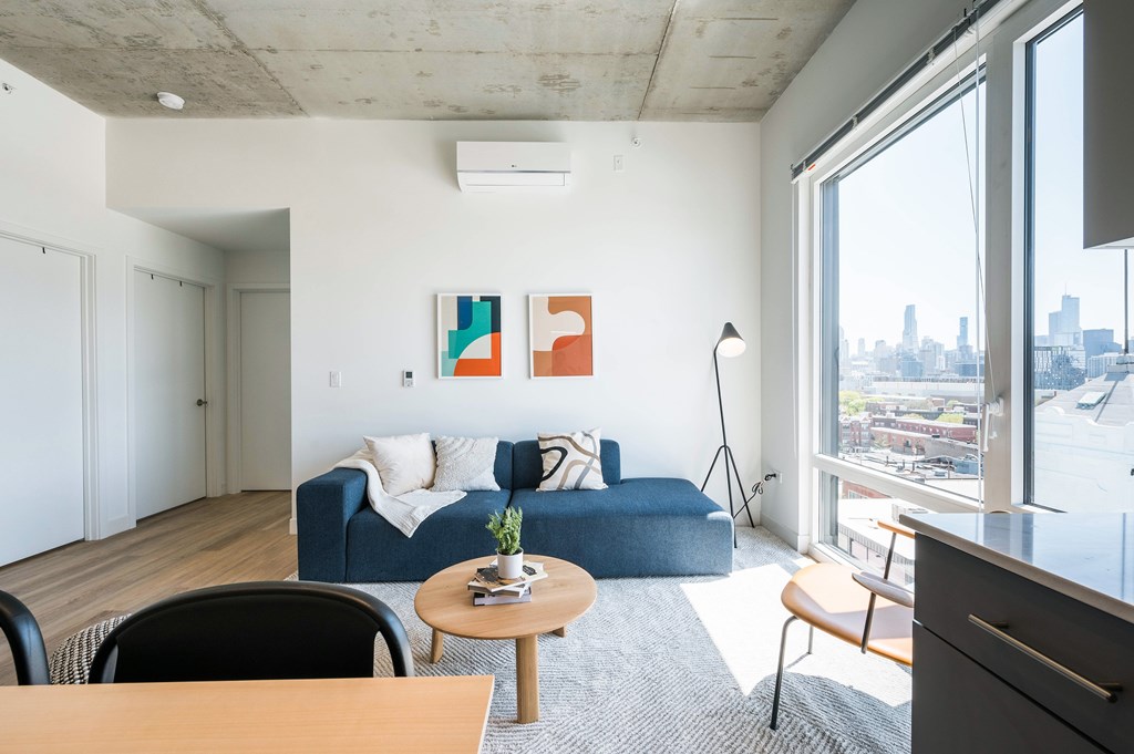 A living room with a blue couch and a painting on the wall.
