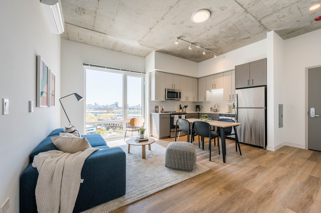 A modern living room with a blue couch and a kitchen area in the background.