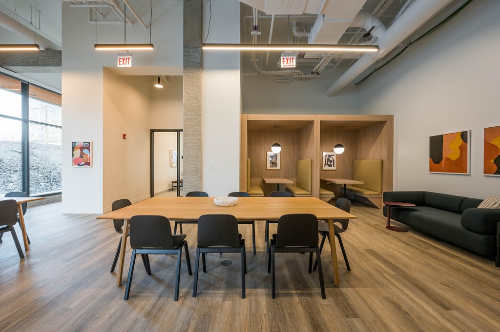 A conference room with a long table and chairs, and two exit signs above it.