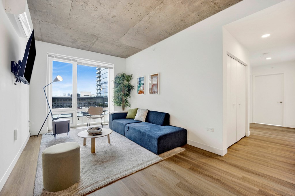 A living room with a blue couch and a television on the wall.