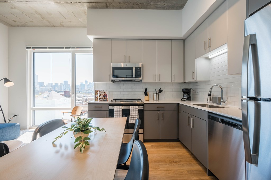 A modern kitchen with a wooden table and stainless steel appliances.