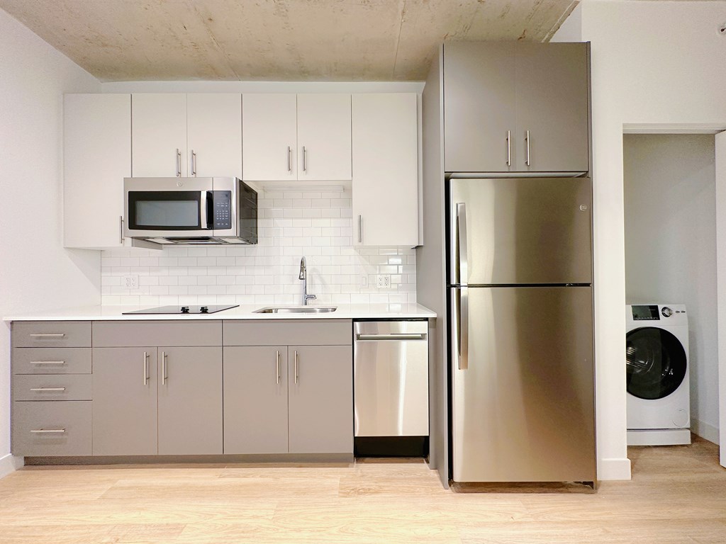 A modern kitchen with a stainless steel refrigerator and microwave above the counter.