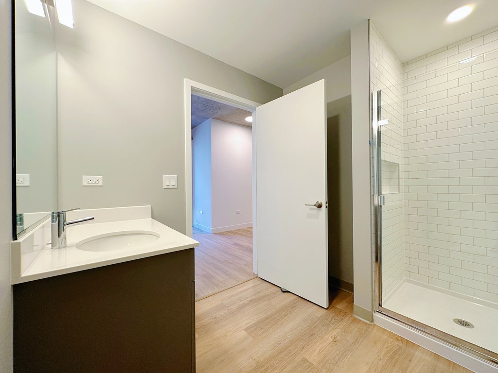 A bathroom with a sink, mirror, and shower.