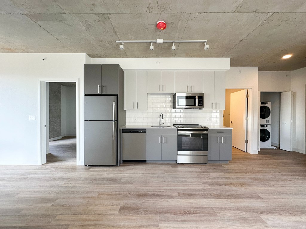 A kitchen with a refrigerator, microwave, oven, and sink.