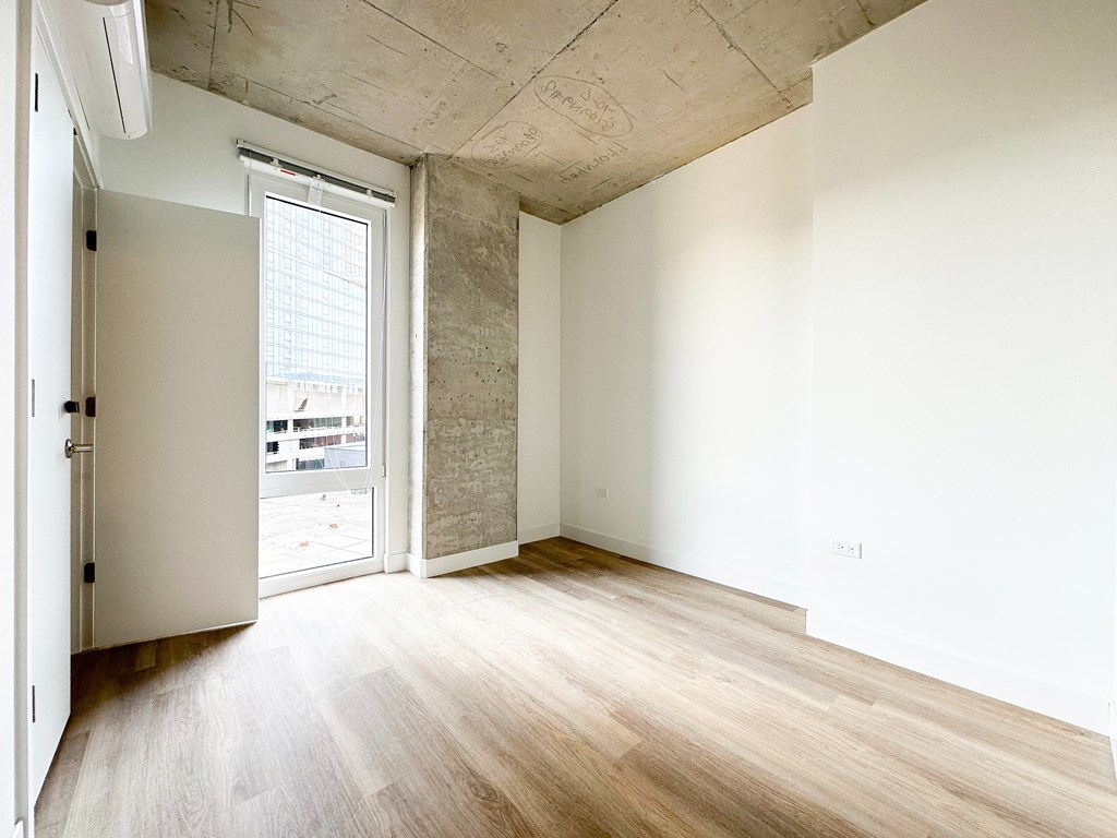 A room with a wooden floor and a concrete ceiling.