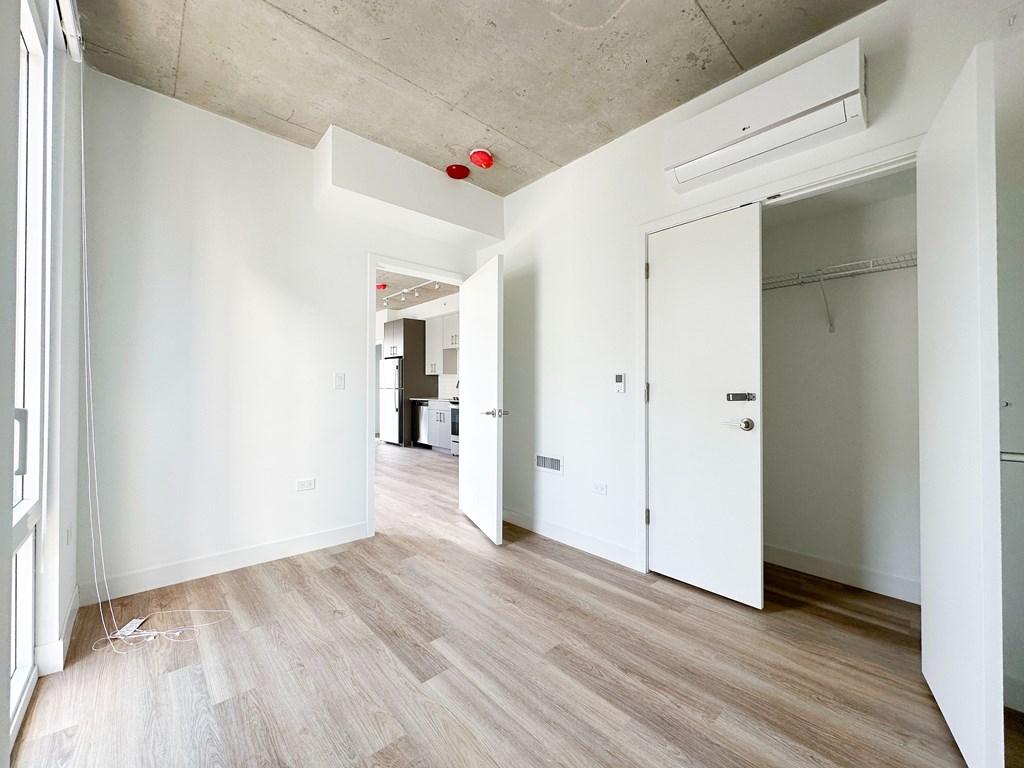 A room with white walls and wooden flooring with a door on the right.
