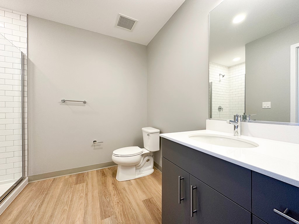 A white toilet sits in a bathroom with a white sink and a mirror.