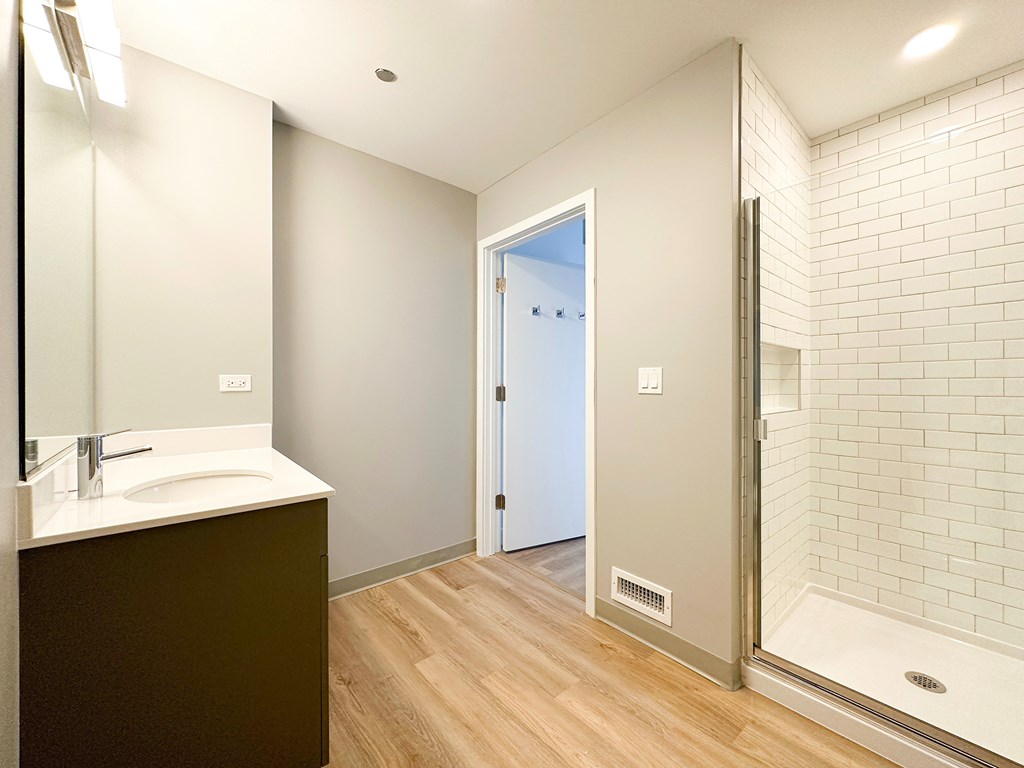 A bathroom with a white sink and a glass shower door.