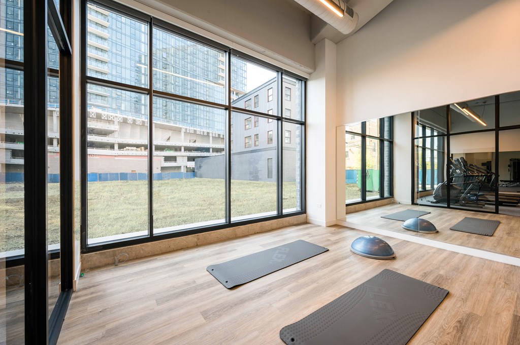 A yoga studio with a view of the city outside the large windows.